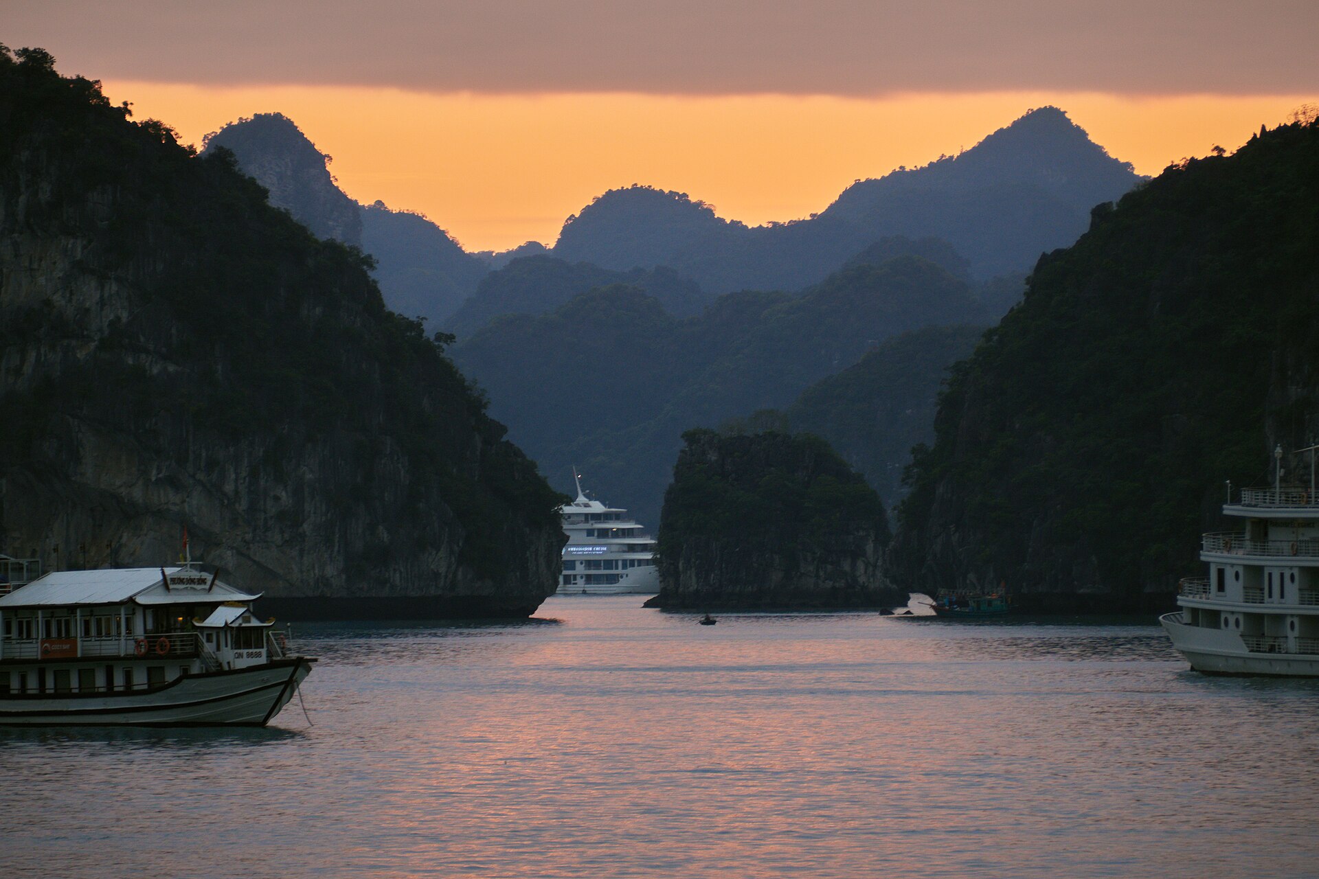 Cruise boats among the limestone islands of Ha Long Bay at sunset