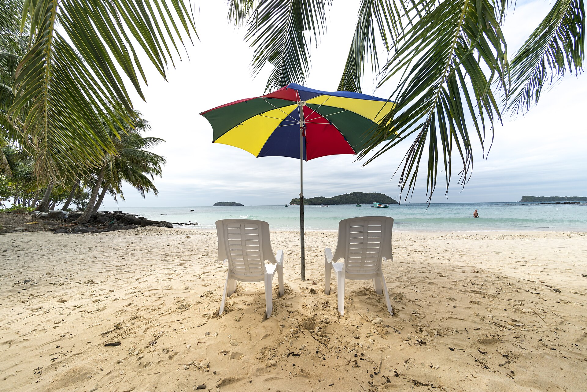 Two chairs under a beach umbrella on a palm-lined beach in Phu Quoc